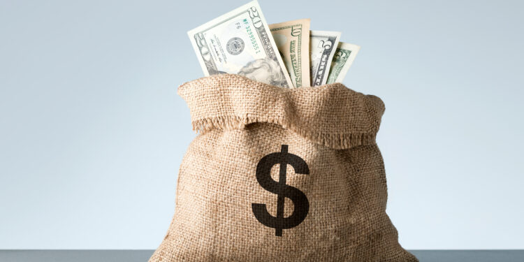 burlap with dollar banknotes on gray background. bribe or bonus
