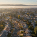 firefly gemini flash aerial view of gilroy neighborhoods at sunrise, gentle fog over hills, warm golden li 635560